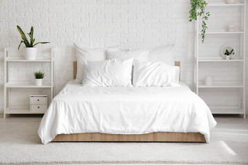 Interior of modern bedroom with comfortable bed and shelving units