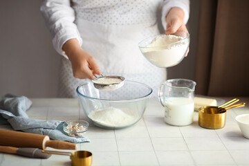 Woman preparing traditional cinnamon rolls in kitchen