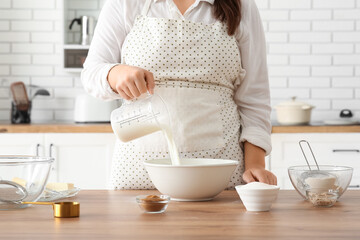 Woman preparing traditional cinnamon rolls in kitchen