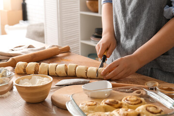 Woman preparing traditional cinnamon rolls in kitchen