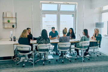 Diverse Business Team Discussing Projects in a Modern Glass Office.