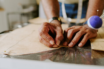Unrecognizable male hands doing darts on cotton stencil and metallic fabric