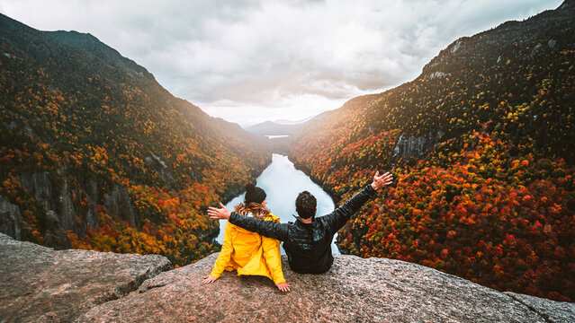 Autumn Fall Foliage Indian Head Adirondacks Hiking Adventure Couple Sit Together, Arms Raised On Top of Mountain at Sunset. Exciting Landscape