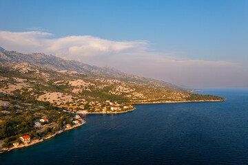 Obraz premium Aerial view of a picturesque coastline with mountains and serene waters on a sunny day. 