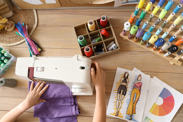 Fashion designer sewing clothes on wooden table, top view