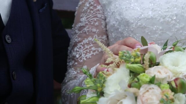 Wedding day. Bride and groom putting hands on dridal bouquet, demonstrating rings. Tenderness of future family. High quality FullHD footage
