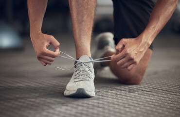 Man, fitness and tying shoes with laces at gym in preparation for running, workout or exercise. Closeup of male person, runner or athlete tie sneakers and getting ready for training at health club