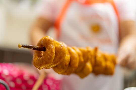 Woman serving skewer of delicious peruvian picarones fritters