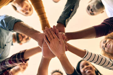Happy, people and hands together with motivation, commitment and smile from below for teamwork. Diversity, closeup and collaboration with group huddle to show solidarity, trust and bonding with care