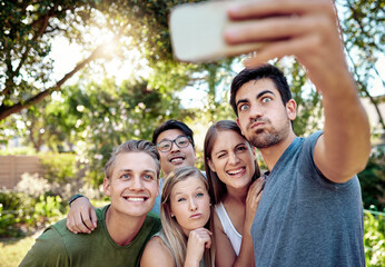 Funny face, selfie and smile with group of friends outdoor in nature together for bonding or profile picture. Comedy, picnic or social media with men and women in park for photograph of break