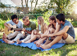 Guitar, friends and park with music, picnic and outdoor together for summer party with drinks. Diversity, bonding and weekend gathering with happy people and listening to song with group in backyard