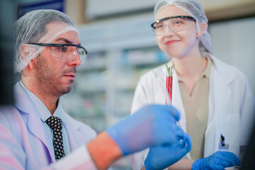 scientists perform experiments and record data. people arranges equipment with test tubes and chemicals for producing medicine and biochemistry. man hold tubes of chemical liquids and plant samples.