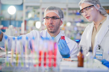 scientists perform experiments and record data. people arranges equipment with test tubes and chemicals for producing medicine and biochemistry. man hold tubes of chemical liquids and plant samples.