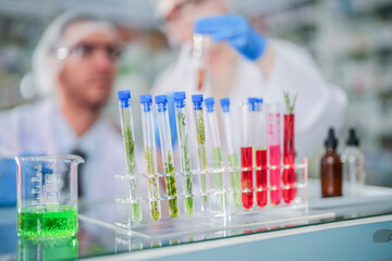 scientists perform experiments and record data. people arranges equipment with test tubes and chemicals for producing medicine and biochemistry. man hold tubes of chemical liquids and plant samples.