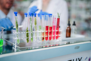 scientists perform experiments and record data. people arranges equipment with test tubes and chemicals for producing medicine and biochemistry. man hold tubes of chemical liquids and plant samples.