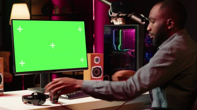 Gamer using keyboard and mouse to play videogame on gaming PC isolated screen monitor. Man in apartment at night using high tech computer peripherals to defeat foes on mockup display