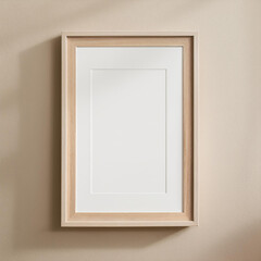 Simple wooden frame hangs on a beige wall background. The frame is empty, ready to be filled with a new artwork.