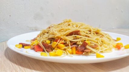 Homemade recipe classic aglio e olio pasta with smoked beef and corn, close-up in a white plate on the table