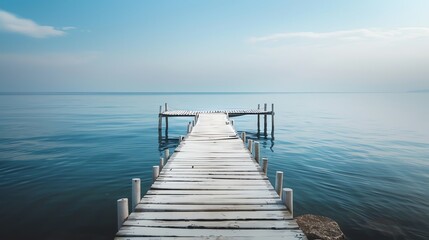 Obraz premium A wooden pier stretches out into a calm, blue lake.