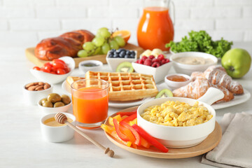 Tasty breakfast. Scrambled eggs in bowl, cut bell pepper, honey and other food on light table