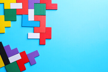 Obraz premium Colorful wooden puzzle pieces on light blue background, top view. Space for text