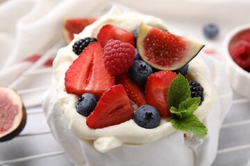 Pavlova cake (meringue dessert) with whipped cream, fresh berries, mint and fig on table, closeup