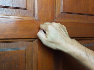 Close up photo of a man's hand knocking on a door