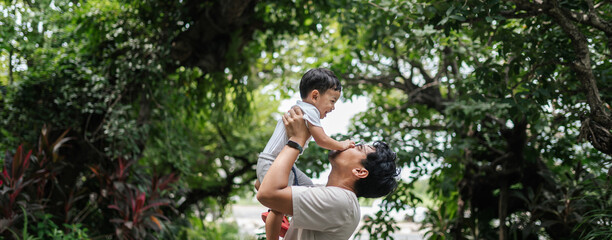 Asian father playing with son, both laughing with joy, capturing a moment of pure happiness and strong family bonding.