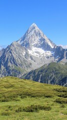 Obraz premium Majestic Mountain Peak with Snow and Green Grass in Alpine Landscape