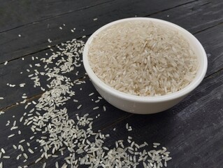 Rice in white bowl on the black wooden table 