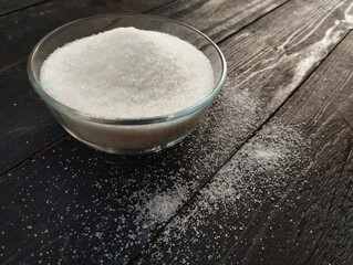 sugar in a bowl on the black wooden table. Food ingredient 
