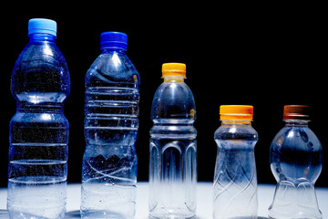 plastic water bottles standing parallel isolated on black background with empty copy space.