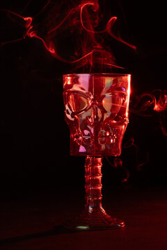 copa de calavera huesuda con humo alrededor y fondo negro con luz roja