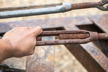 A hand is holding a rusty bolt.