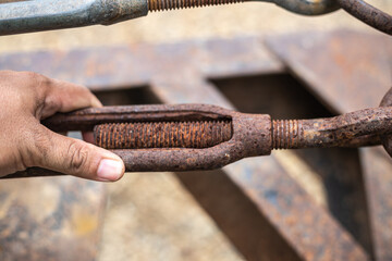 A hand is holding a rusty bolt