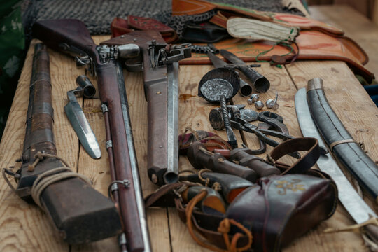 Set of antique firearms on wooden table. Rifles, bayonets, saber, peak tips, selective focus.