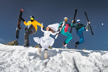 Group of happy young friends skiers and snowboarders are having fun and jumping from snowdrift. Ski resort or winter weekend concept