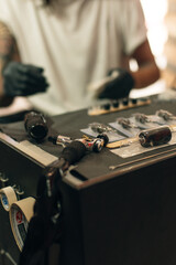 Tattoo artist workplace with machine and bottles with black tattoo ink