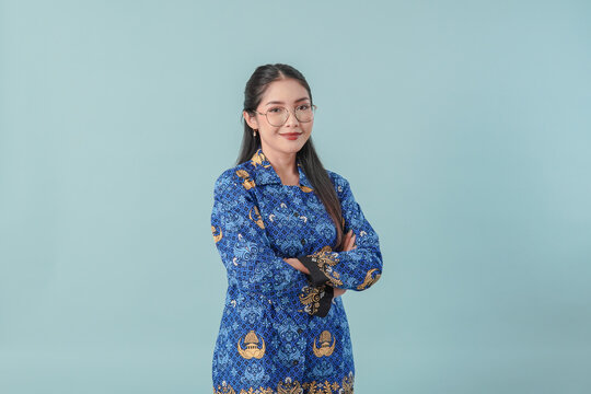 Confident government worker woman wearing blue batik uniform smiling with her arms crossed.