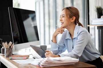 Happy Young attractive businesswoman working on her project with  computer and tablet in modern office room.
