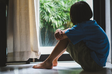 Crying girl, victim of bullying, abuse, violence, depressed patient, offering psychotherapy sitting on floor near door in the room. She was bullied, unhappy, upset, feel sick. Lonely concept.