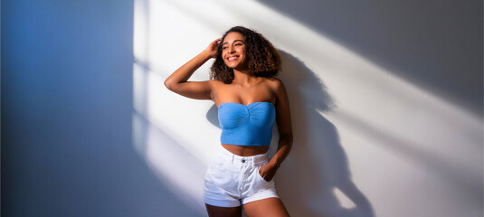 A portrait of a Black woman wearing a light blue tube top and white shorts.