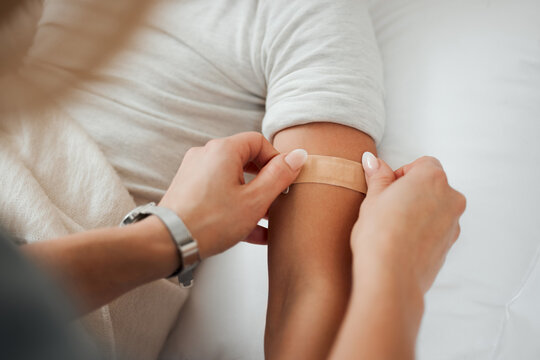 Hands, arm and woman with bandage for kid in home bedroom for wellness or healthcare. Family, first aid and mother apply bandaid plaster on hurt or injured child for injury or medical injection