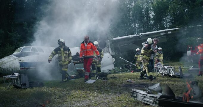 Firefighters and Emergency Rescue Staff Navigate the Wreckage of a Plane Crash in a Forest, Extracting Survivors and Administering Aid. Intense Rescue Operation as Teams Battle Fire to Save Lives