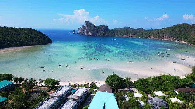 Kho Phi phi island tonsai pier boats arrive docked on turquoise water on a sunny day in thailand. Dramatic aerial view flight panorama overview drone