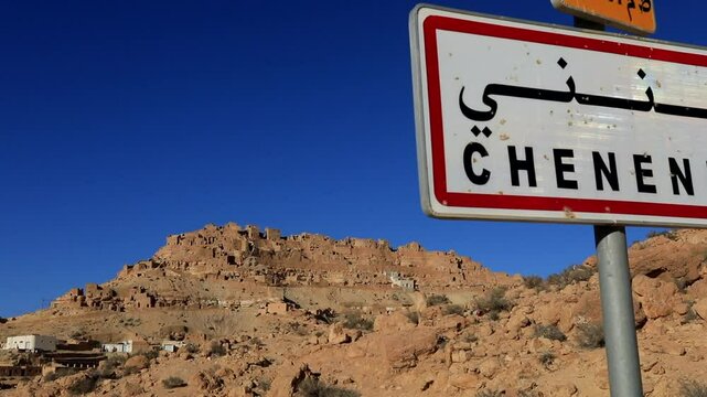 Road sign for the historic village of Chenini against a clear blue sky in the Tunisian desert