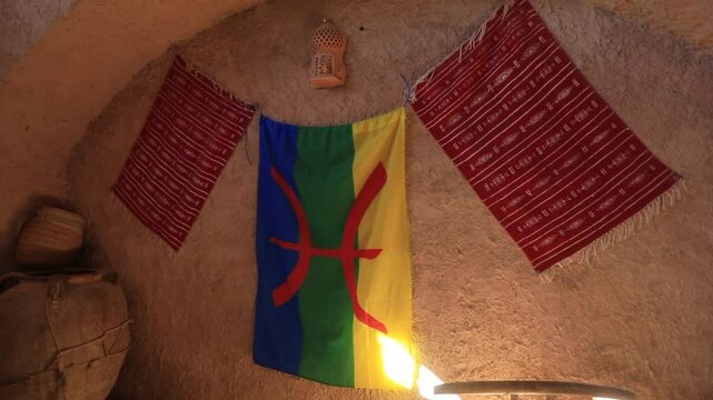 Colorful Berber flag and traditional rugs adorn the wall of a ksar in Tunisia