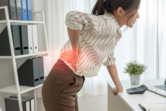 Asia beautiful woman holding her lower back while and suffer from unbearable pain health and problems, chronic back pain, backache in office syndrome, scoliosis, herniated disc, muscle inflammation