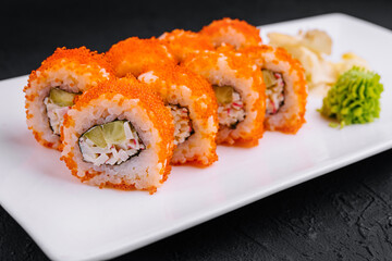 California sushi rolls covered with tobiko red caviar lying on white plate