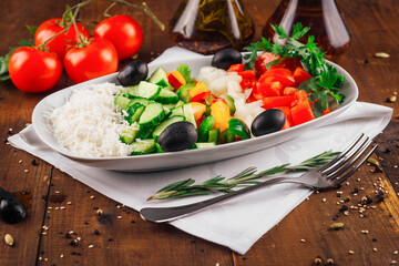 Shopska salad with feta cheese, tomatoes, cucumber and olives resting on a wooden table